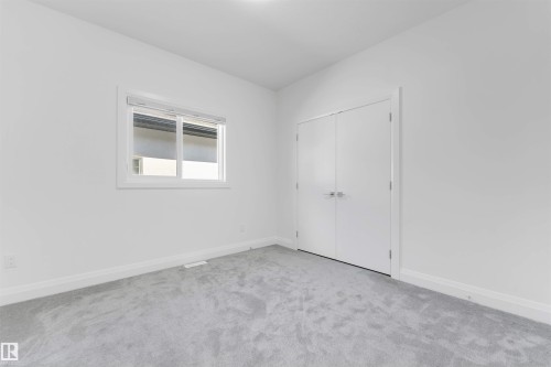 Room featuring light gray carpeting, crisp white walls, a double-panel closet door with brushed nickel hardware, and a single window with blinds - 1923 19 Avenue, Edmonton, AB - Indoor Photo Showing Other Room
