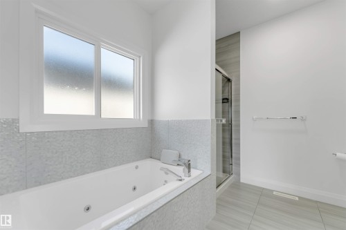 Bathroom featuring a built-in jetted tub with tile surround, a frosted window, and a glass-enclosed shower stall - 1923 19 Avenue, Edmonton, AB - Indoor Photo Showing Bathroom
