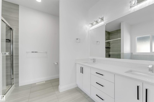 Contemporary bathroom featuring a double vanity with white cabinetry, black hardware, and integrated sinks - 1923 19 Avenue, Edmonton, AB - Indoor Photo Showing Bathroom