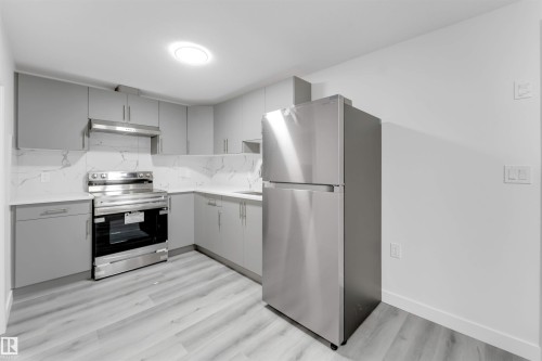 Contemporary kitchen featuring light gray cabinetry, stainless steel appliances, and wood-finish flooring - 1923 19 Avenue, Edmonton, AB - Indoor Photo Showing Kitchen