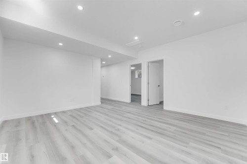 Spacious room featuring light wood-finish flooring, white walls, recessed ceiling lighting, and white baseboards - 1923 19 Avenue, Edmonton, AB - Indoor Photo Showing Other Room