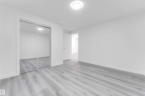 Spacious room featuring light wood-finish flooring, bright white walls, and a recessed ceiling light - 1923 19 Avenue, Edmonton, AB - Indoor Photo Showing Other Room