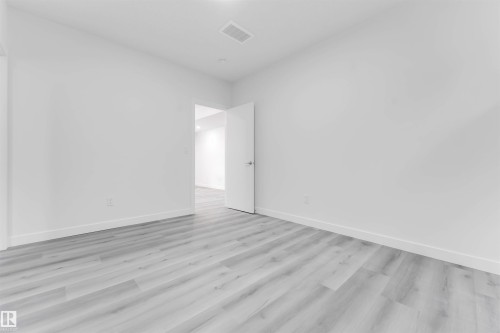 Spacious interior room featuring light wood-finish flooring, white baseboards, and neutral wall tones - 1923 19 Avenue, Edmonton, AB - Indoor Photo Showing Other Room