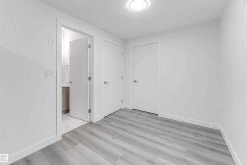 Bright interior space featuring light wood-finish flooring, white walls, and a contemporary ceiling light fixture - 1923 19 Avenue, Edmonton, AB - Indoor Photo Showing Other Room