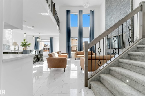 Two-story living area featuring a stone accent wall, high ceilings, large windows with full-length drapery, and polished tile flooring - 1923 19 Avenue, Edmonton, AB - Indoor Photo Showing Other Room