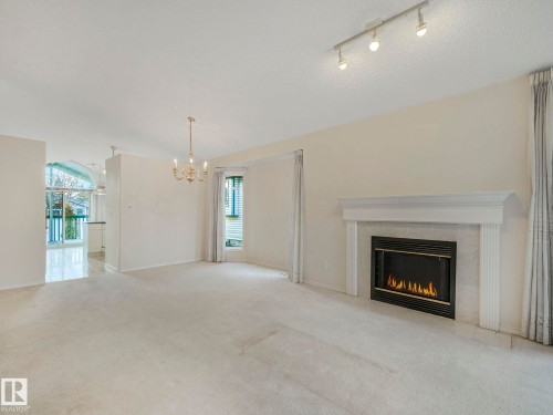 Living area featuring a classic fireplace with a white mantel and tile surround - 23 9731 174 Street, Edmonton, AB - Indoor Photo Showing Living Room With Fireplace