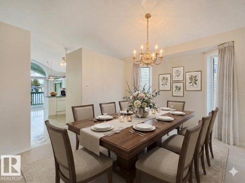 Dining area featuring a gold-tone chandelier, neutral wall tones, and architectural wall cutouts - 23 9731 174 Street, Edmonton, AB - Indoor Photo Showing Dining Room