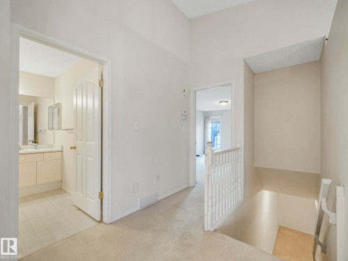 Carpeted hallway with a vaulted ceiling, providing access to a bathroom with a vanity and a separate room with a window - 23 9731 174 Street, Edmonton, AB - Indoor Photo Showing Other Room