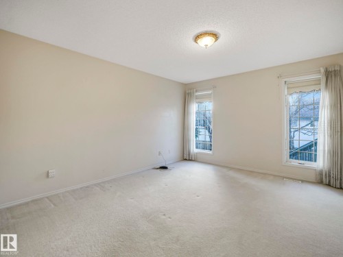 Spacious interior room with neutral-toned walls, textured ceiling, and light-colored carpeting - 23 9731 174 Street, Edmonton, AB - Indoor Photo Showing Other Room