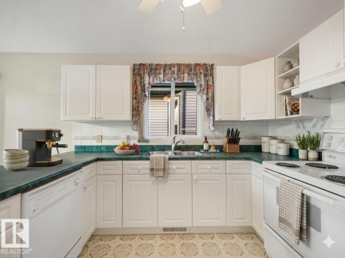 White cabinetry, green countertops, and a white tile backsplash define this kitchen - 23 9731 174 Street, Edmonton, AB - Indoor Photo Showing Kitchen With Double Sink