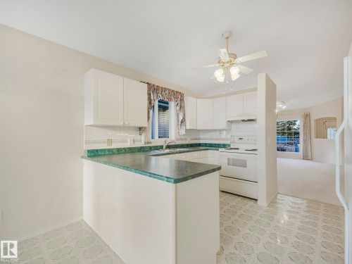 Kitchen with white cabinetry, green countertops, and a white appliance suite - 23 9731 174 Street, Edmonton, AB - Indoor Photo Showing Kitchen