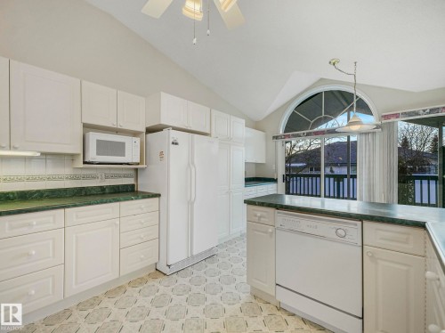 Kitchen featuring a vaulted ceiling with a ceiling fan, white cabinetry, and dark countertops - 23 9731 174 Street, Edmonton, AB - Indoor Photo Showing Kitchen