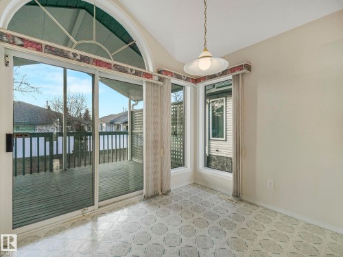 Light-filled interior featuring a large sliding glass door, arched transom window, corner window array, patterned floor tiles, and a suspended ceiling fixture - 23 9731 174 Street, Edmonton, AB - Indoor Photo Showing Other Room