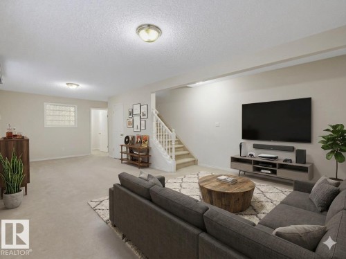 Expansive lower-level living area featuring neutral carpeting, a staircase with white balusters, and recessed lighting - 23 9731 174 Street, Edmonton, AB - Indoor