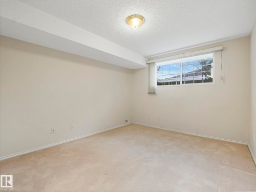 Carpeted room with a multi-pane window, flush-mount ceiling light, painted walls, and baseboard trim - 23 9731 174 Street, Edmonton, AB - Indoor Photo Showing Other Room