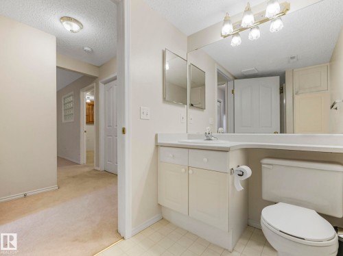 Bathroom featuring a white vanity with integrated sink, a large wall-mounted mirror, and a five-light vanity fixture - 23 9731 174 Street, Edmonton, AB - Indoor Photo Showing Bathroom
