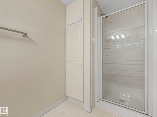 Tiled shower enclosure with frosted glass door, adjacent to built-in cabinetry and tiled flooring - 23 9731 174 Street, Edmonton, AB - Indoor Photo Showing Bathroom