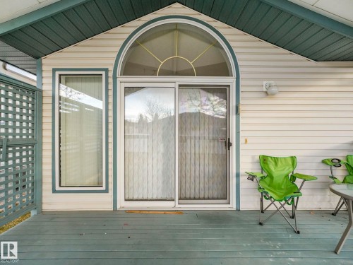 Covered deck with a lattice privacy screen, featuring a sliding glass door and an arched transom window - 23 9731 174 Street, Edmonton, AB - Outdoor With Deck Patio Veranda With Exterior