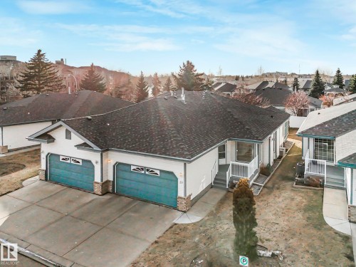 Single-story residence featuring light-colored siding, a dark shingle roof, and a two-car garage with teal doors - 23 9731 174 Street, Edmonton, AB - Outdoor