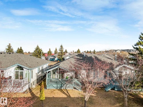 Two-story property featuring a front-facing deck with painted railings, a lower-level walkout patio, and multiple windows - 23 9731 174 Street, Edmonton, AB - Outdoor