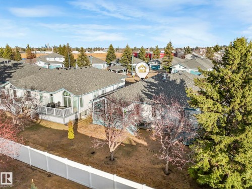 Residential property featuring a shingle roof, rear deck with white railing, and a private backyard with mature trees - 23 9731 174 Street, Edmonton, AB - Outdoor