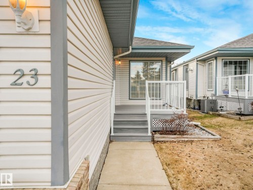 Entryway featuring light-colored siding, a concrete walkway, and a grey-toned porch with white railings - 23 9731 174 Street, Edmonton, AB - Outdoor With Exterior