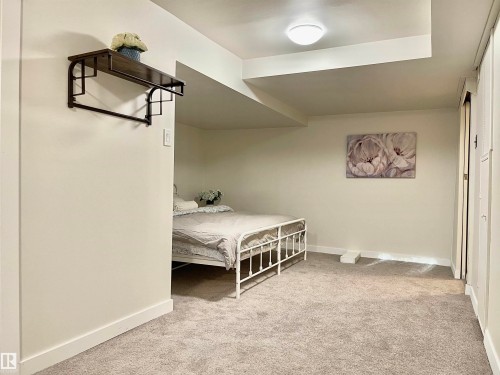 Carpeted room featuring light-colored walls and a wall-mounted shelf with integrated hanging rod - 11681 72 Avenue, Edmonton, AB - Indoor Photo Showing Other Room