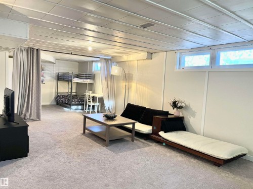 Finished lower level featuring light-toned carpet flooring, panel walls, and a drop ceiling - 11681 72 Avenue, Edmonton, AB - Indoor Photo Showing Basement
