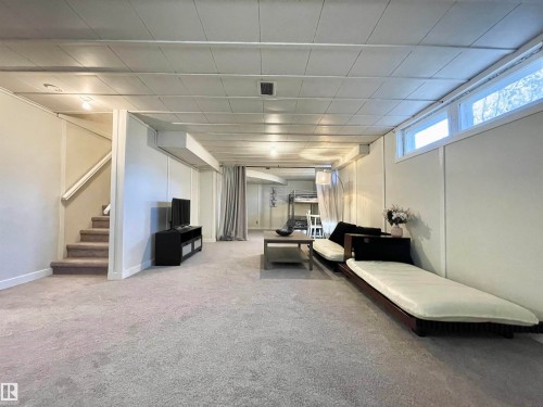 Spacious lower level featuring light-toned carpeting, white paneled walls, and a suspended ceiling with integrated lighting - 11681 72 Avenue, Edmonton, AB - Indoor