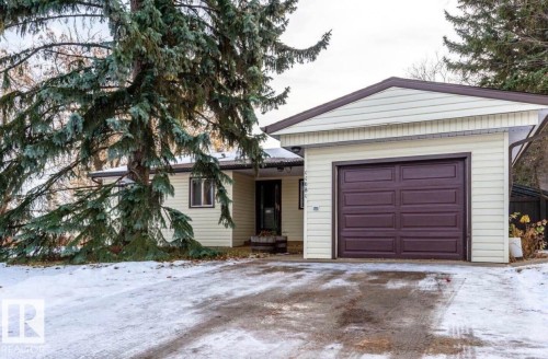 Attached garage with a brown panel door, light-colored siding, and a paved driveway - 11681 72 Avenue, Edmonton, AB - Outdoor