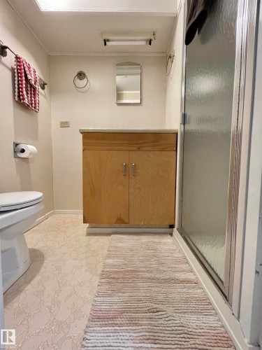 Bathroom featuring a light-toned vanity with cabinet storage, a shower enclosure with a frosted glass door, a wall-mounted toilet, and patterned flooring - 11681 72 Avenue, Edmonton, AB - Indoor Photo Showing Bathroom