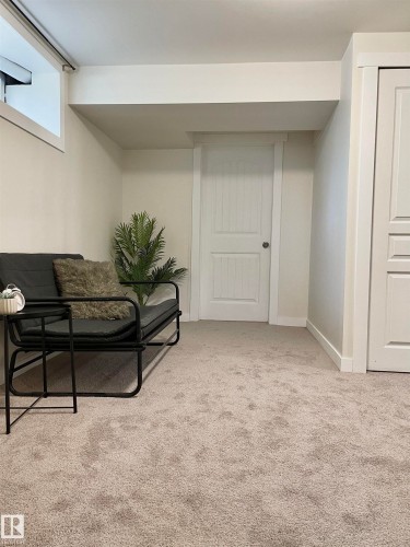 Carpeted room featuring a white paneled door, a second white door with vertical paneling, and a horizontal window - 11681 72 Avenue, Edmonton, AB - Indoor