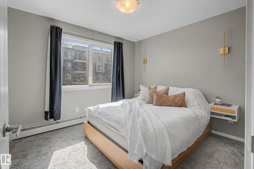 Spacious room featuring a large window, light gray wall paint, and gray carpet flooring - 217 394 Windermere Road, Edmonton, AB - Indoor Photo Showing Bedroom