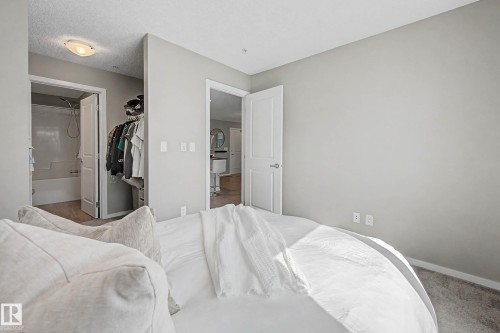 Neutral-toned interior with light gray walls and a textured ceiling - 217 394 Windermere Road, Edmonton, AB - Indoor Photo Showing Bedroom