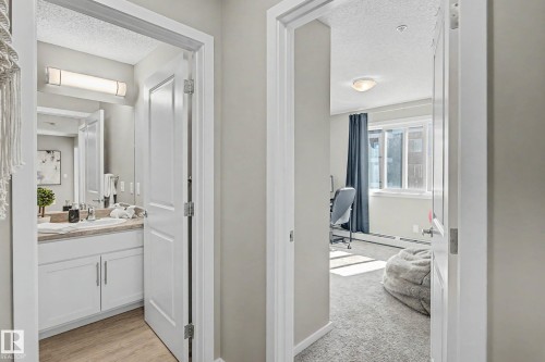 Hallway featuring two white paneled doors, light gray wall paint, and recessed lighting - 217 394 Windermere Road, Edmonton, AB - Indoor Photo Showing Bathroom
