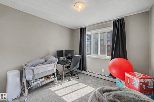 Bright room featuring a large window, soft gray wall paint, and gray carpet flooring - 217 394 Windermere Road, Edmonton, AB - Indoor