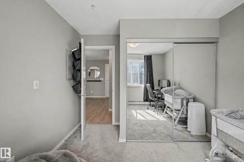Interior room featuring light gray wall paint and textured carpeting - 217 394 Windermere Road, Edmonton, AB - Indoor