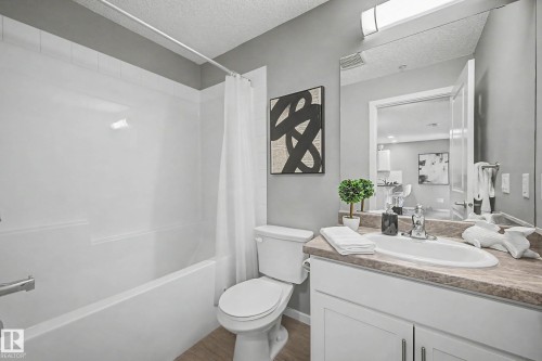 Full bathroom featuring a single vanity with a laminate countertop, an integrated sink, and white cabinetry - 217 394 Windermere Road, Edmonton, AB - Indoor Photo Showing Bathroom