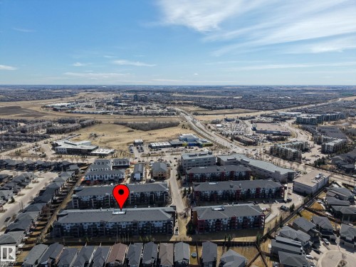 Modern multi-story residential building with a dark gray roof and red/gray exterior accents - 217 394 Windermere Road, Edmonton, AB - Outdoor With View
