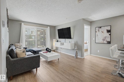 Spacious living area featuring wood-finish flooring, light gray walls, and white trim - 217 394 Windermere Road, Edmonton, AB - Indoor Photo Showing Living Room