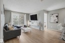 Spacious living area featuring wood-finish flooring, light gray walls, and white trim - 217 394 Windermere Road, Edmonton, AB  - Indoor Photo Showing Living Room 