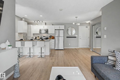 Open-concept living space featuring a kitchen with white cabinetry and stainless steel appliances - 217 394 Windermere Road, Edmonton, AB - Indoor Photo Showing Kitchen With Stainless Steel Kitchen