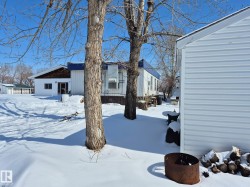 The property features a white exterior with a blue roof, and a separate structure with white siding - 