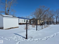 The property features a white shed with a grey roof and a metal fence - 