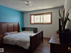 The room features wood flooring, a window with wood trim, and a blue accent wall - 