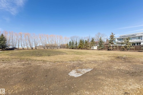 Expansive land parcel featuring a perimeter of mature deciduous and evergreen trees, with a portion of a multi-level structure visible in the background - 2B Discovery Avenue, Rural Sturgeon County, AB 