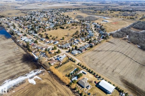 Aerial perspective showcasing a residential community surrounded by agricultural fields and natural tree lines - 2B Discovery Avenue, Rural Sturgeon County, AB 