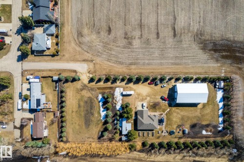 Aerial perspective showcasing a sprawling property featuring a substantial main residence with a dark shingle roof, a large white metal outbuilding, and extensive surrounding land - 2B Discovery Avenue, Rural Sturgeon County, AB 