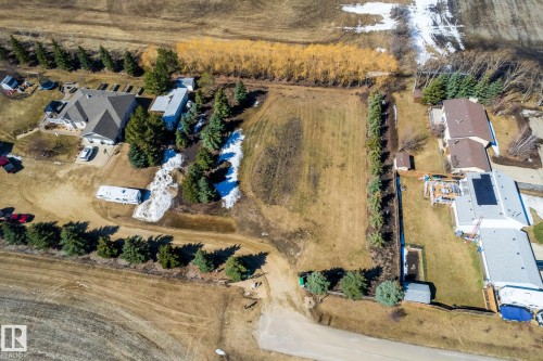 Expansive land parcel featuring a generous flat grassy area, mature evergreen trees, and perimeter fencing - 2B Discovery Avenue, Rural Sturgeon County, AB 
