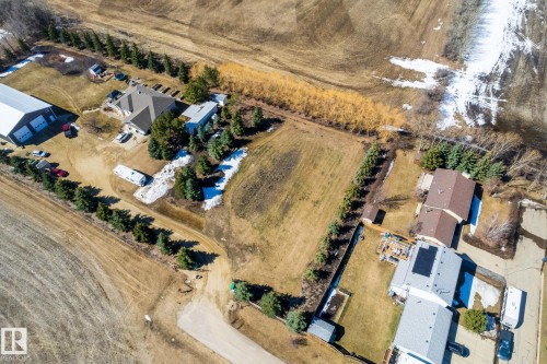 Expansive lot featuring a main residence with a brown shingle roof, a large detached garage/shop with multiple bays, a separate accessory structure, and mature evergreen tree lines bordering the property - 2B Discovery Avenue, Rural Sturgeon County, AB 